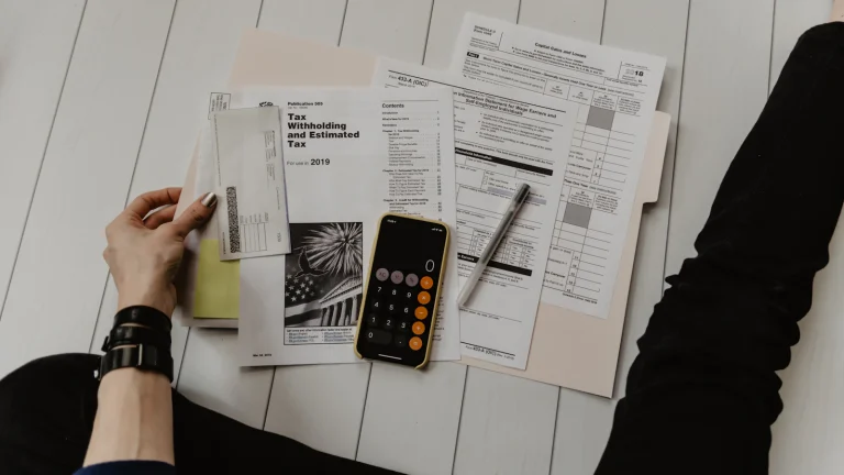 Person reviewing numbers with a calculator and paperwork