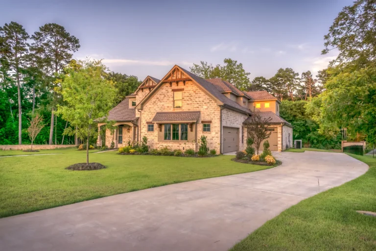 Stone and brick family home at sunset with a long driveway