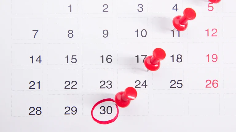 Wall calendar with red push pins marking key dates, like the deadlines in a foreclosure timeline