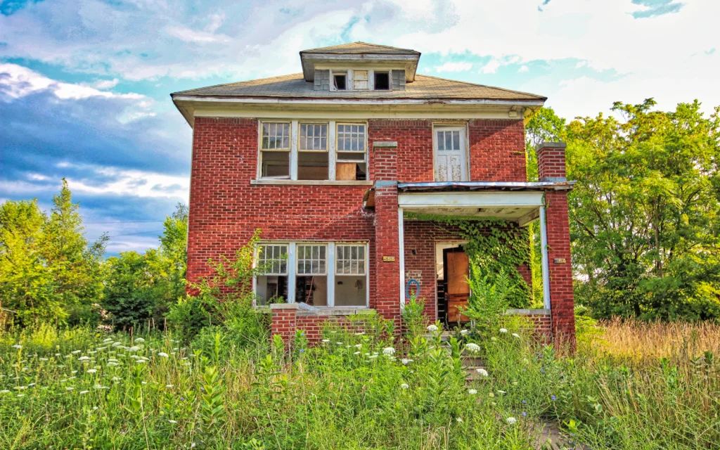 Older two-story brick house with an overgrown yard